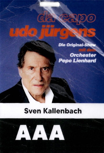 Event badge featuring a photo of Udo Jürgens with text promoting 'da capo udo jürgens Die Original-Show mit dem Orchester Pepe Lienhard' and the name Sven Kallenbach above large AAA access designation.